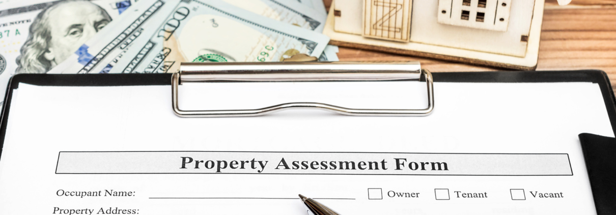 property assessment form on clipboard with pen, cash and toy house on table below