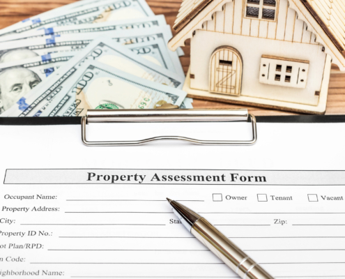 property assessment form on clipboard with pen, cash and toy house on table below